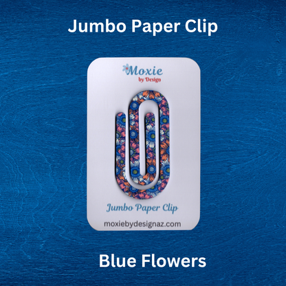 Colorful jumbo paper clip with blue flower design on a display card against a textured blue background.
